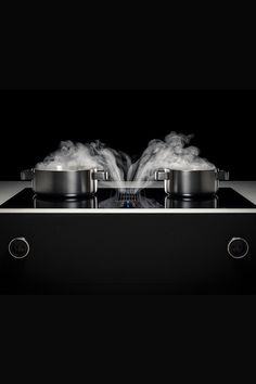 two pots on top of a stove with steam coming out of the burners and in front of them