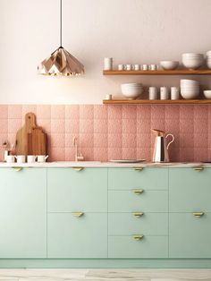 a kitchen with green cabinets and pink tiles on the backsplash, gold handles