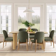 a dining room table with green chairs and a potted plant