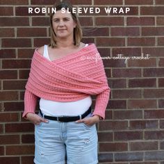 a woman standing in front of a brick wall wearing a pink knitted shawl