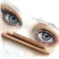 two pencils sitting on top of a drawing of an eye