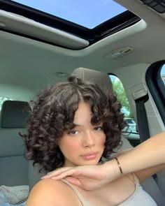 a woman sitting in the back seat of a car with her hand on her chin