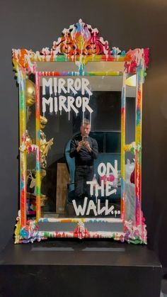 a mirror with the words mirror mirror on the wall in front of it and a man taking a selfie