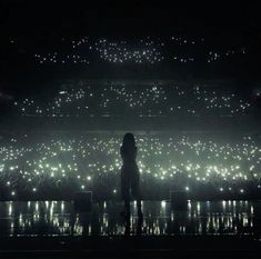 a person standing in front of a stage with lots of bright lights on it at night