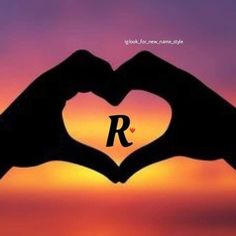 two hands making a heart shape with the letter r in front of an orange and purple sunset