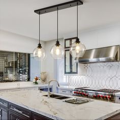 a kitchen with marble counter tops and hanging lights