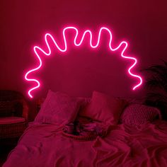 a bed with pink neon lights on the headboard and pillows in front of it