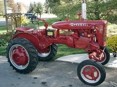 an old red farmall tractor parked on the street