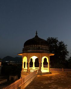 a gazebo lit up at night with the moon in the sky