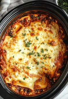 a crock pot filled with lasagna sauce and topped with parmesan cheese