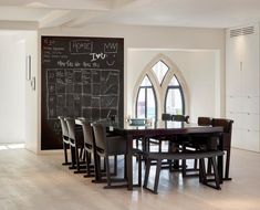 a dining room table with chairs and a chalkboard on the wall in front of it