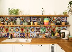 a kitchen with colorful tiles on the wall and wooden counter tops, along with white cabinets