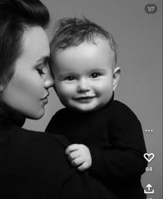 a black and white photo of a woman holding a baby with her face close to the camera