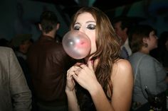 a woman blowing a bubble with her mouth