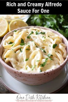 a bowl filled with creamy alfredo sauce and garnished with parsley on the side