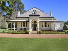 a large white house sitting on top of a lush green field