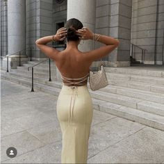 the back of a woman's dress, with her hands on her head and hand in her hair