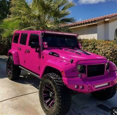 a bright pink jeep is parked in front of a house with palm trees and bushes