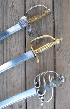 three different types of swords on a wooden surface