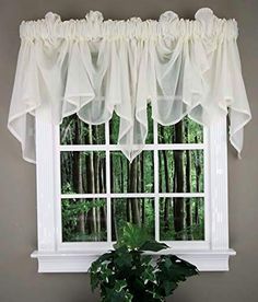 a window with white ruffled curtains and a potted plant