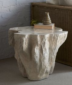 a table with a book on top of it next to a wicker basket and vase