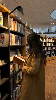 a woman standing in front of a book shelf filled with books