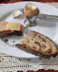 a plate with bread, eggs and an egg yogurt on it sitting on a doily