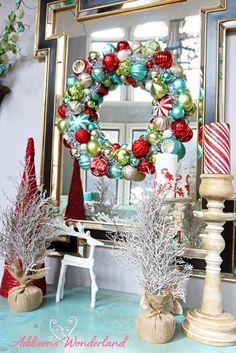 a christmas wreath and other holiday decorations on a table with a mirror in the background