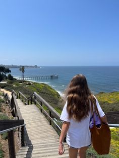 a girl walking up stairs towards the ocean