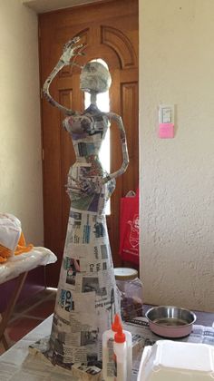 a paper mache is standing in the middle of a table with papers on it