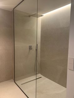 a bathroom with a glass shower stall and tiled floor