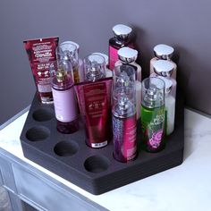 an assortment of different types of body care products on a black tray in front of a gray wall