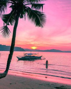 a boat sitting on top of a beach next to the ocean under a pink sky