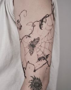 a woman's arm with a spider web and flowers tattoo on the left arm