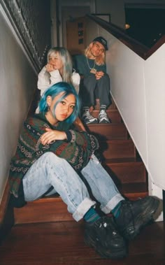 three people are sitting on the stairs with their arms around each other and one person has blue hair