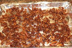 some pecans are sitting on tin foil and ready to be cooked in the oven