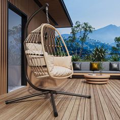 a hanging chair on a wooden deck with mountains in the background