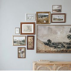 there are many pictures on the wall with frames above it and an old dresser below