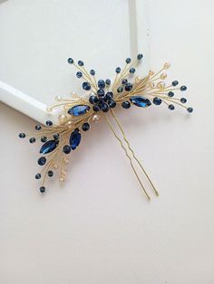 Introducing the elegant gold and blue hair pin: a touch of sophistication for your special occasions. Complete your evening or wedding hairstyle with our exquisite decorative hair pin. This blue hair accessory is designed to add a touch of elegance and charm to your look, ensuring that you stand out on your special day. The bridesmaid hair pin is meticulously crafted using premium crystal beads and pearl beads. The combination of blue and gold creates a striking contrast, making this hairpin a captivating addition to any hairstyle. For your convenience, you can choose between gold or silver wire to complement your personal style and preference. The length of the blue hair pin measures approximately 5.5 inches, providing a perfect balance between style and practicality. It is designed to se Blue And Gold Hair Accessories, Hair Pin, Navy Blue Wedding Hair Accessories, Navy Blue Hair Piece For Wedding, Elegant Blue Hair Accessories For Formal Occasions, Blue And Gold Hair Pins, Decorative Hair Pins, Blue Hair Pins, Navy Blue Hair