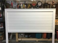 a white headboard sitting on top of a wooden shelf in a room filled with lots of clutter