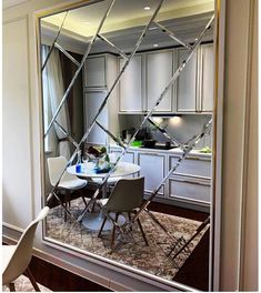 the reflection of a kitchen and dining room in a mirrored wall mirror that is open