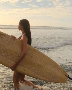 a woman carrying a surfboard into the ocean