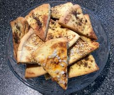 a glass plate filled with sliced up pizza slices on top of a granite countertop