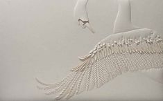 a paper sculpture of a white bird with feathers on it's back and wings spread out