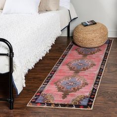 a bed sitting next to a rug on top of a wooden floor