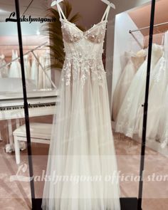 a wedding dress hanging on a rack in front of a mirror with other dresses behind it