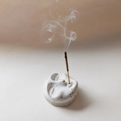 Ceramic face shape round incense stick holder with a burning incense stick in its mouth. Incense Holder Ceramics, Incense Ceramic Holder, Airdry Clay Incense Holders, Diy Insence Holder, Ceramic Insence Holder, Incense Holder Aesthetic, Face Incense Holder, Handmade Ceramics Ideas, Pottery Incense Holder