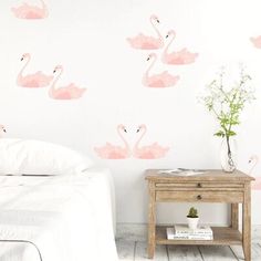 pink flamingo wall decals in a bedroom with white bedding and wooden side table