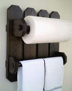 two rolls of toilet paper are hanging on a wooden rack with towel bars attached to it