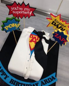 a birthday cake that is shaped like a shirt and tie with the words you're my superhero on it